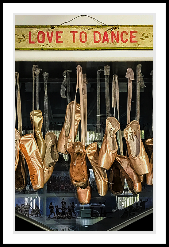 Ballet shoes hanging in a window in a photo titled, Love to Dance.